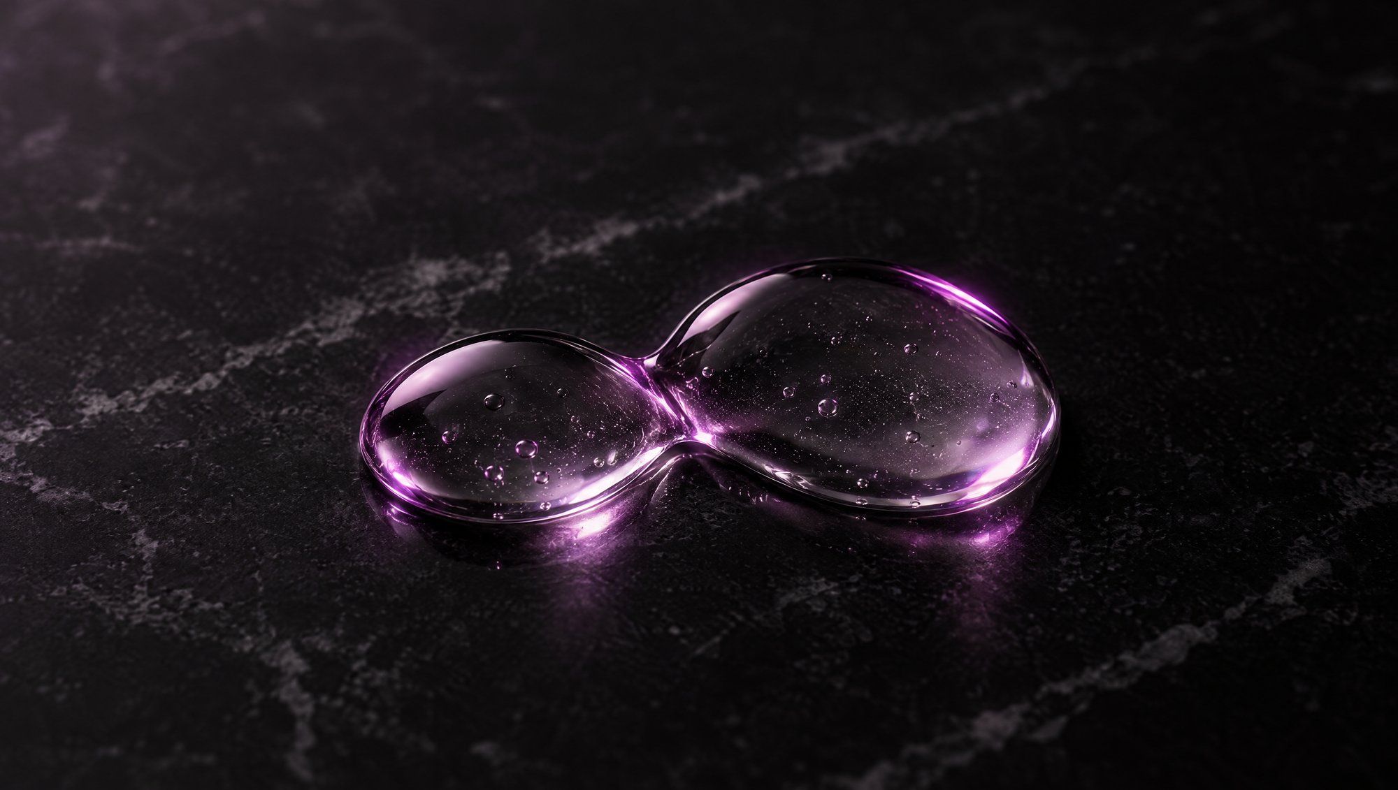 Close-up of two drops of clear gel merging on a dark marble surface, their edges lit in plum.