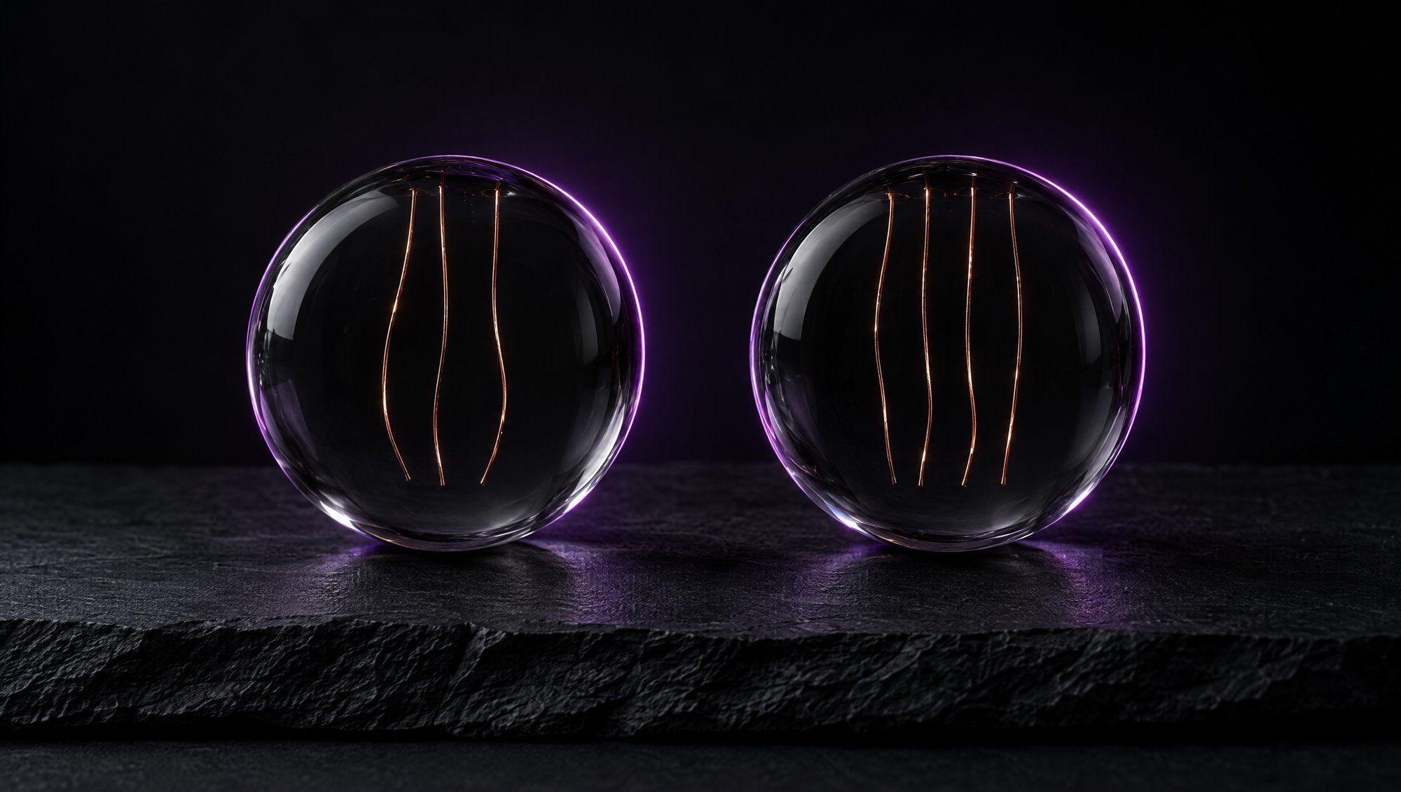 Two clear glass spheres side by side on dark slate, the left holding three thin copper threads and the right holding four, both outlined by a plum rim light.